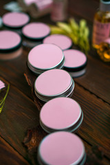 round jars for cosmetics with a pink sticker on a dark wooden table.