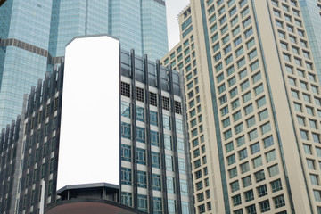 Obraz premium Blank advertising billboard on the Glass wall in a modern office building, Common business skyscrapers, high-rise buildings, architecture raising to the sky, the sun light reflected on the structure