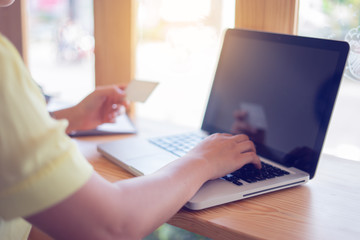 Fototapeta premium Bank, bill.Online payment,women's hands holding laptop and smartphone ,using credit card for shopping online fashion, She typing numbers on computer keyboard at home at the wooden table 