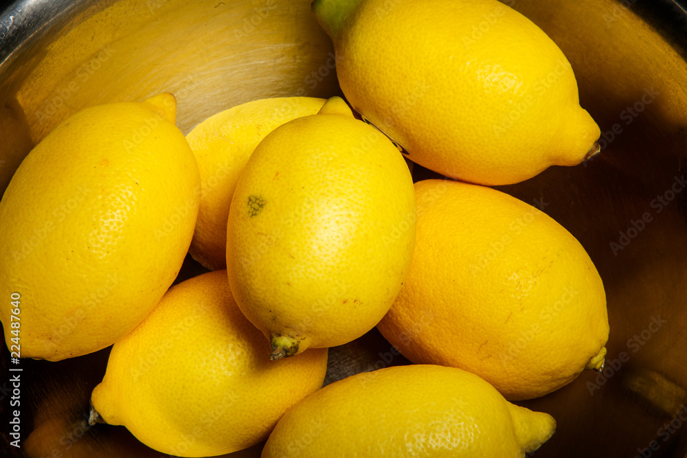 Wall mural closeup many juicy lemons lie in metal bowl