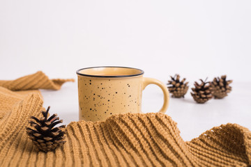Knitted shawl, cup of coffee and cones on white background