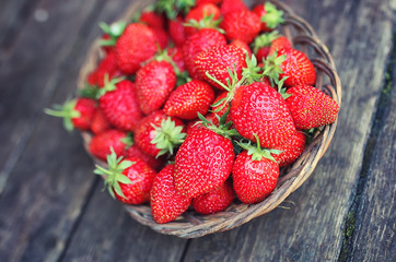 Strawberry in wicker plate on wooden background