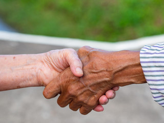 Close-up image of shaking hands between elderly womans. Unity Concept.