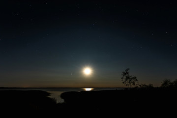 Night moon sky, full moon, Moon over the lake. Night landscape. Reflection of the rays from the moon in the water.