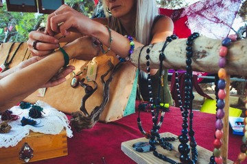 A woman selling homemade craft jewelry from a market stall at a hippy festival