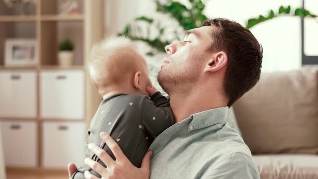 family, parenthood and people concept - happy father with little baby daughter at home