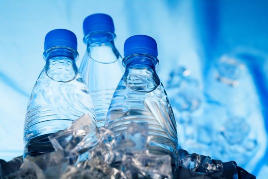 Three Bottles of Water in Ice Bucket on the Blue Background