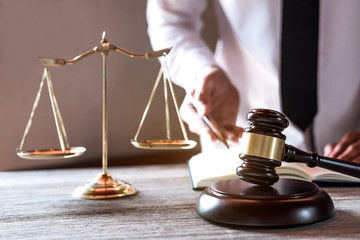 Legal law, advice and justice concept, Professional male lawyers working on courtroom sitting at the table and signing papers with gavel and Scales of justice