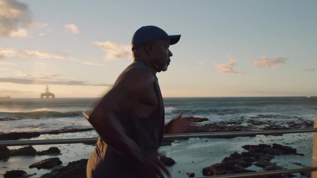 fit senior woman runner overtaking in running workout competition exercising endurance on calm beautiful ocean seaside at sunset close up