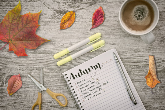 The arrival of autumn is a good time to face new resolutions for the new season, written on a to-do list in a notebook on a wooden deskt with dry leaves