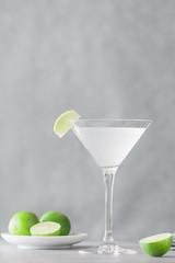 The alcoholic Kamikaze cocktail in a cocktail glass with a wedge lime on a table. Cocktail is made of equal part of vodka, lime juice and triple sec.