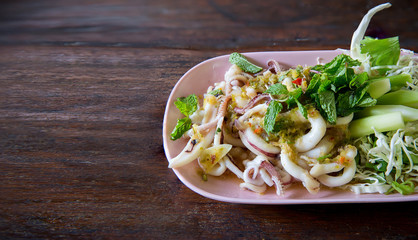 Squid spicy and sour salad wood table background, thai traditional food , thai seafood cuisine, image for menu list,background,wallpaper and copy space