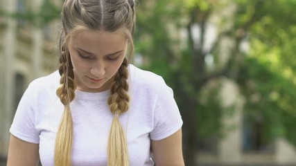 Teenage girl reading book outdoors, remembering information, preparing for exam