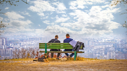 People sitting on a bench looking at city Plovdiv.