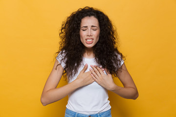 Displeased woman with heartache isolated over yellow background.