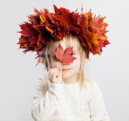 Cute child girl in autumn leaves on head, portrait