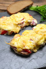 Baked in oven meat with mushrooms, tomato and cheese, servet on stone plate