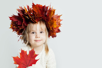 Pretty little girl holding autumn leaves on background with copy space