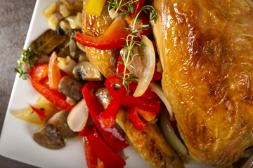 Baked whole chicken with fried vegetables like bell pepper, onion and garlic