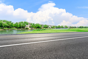 Asphalt road and apartment buildings with woods in the city suburbs