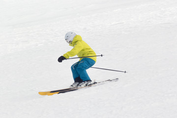Skier in bright clothing skiing downhill. Side view