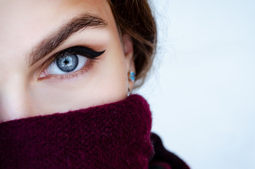 Close-up portrait of a woman in a scarf and hat with beautiful blue eyes