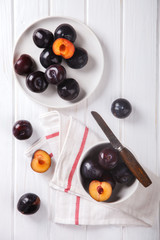 Plums in plate on wooden white background.selective focus.