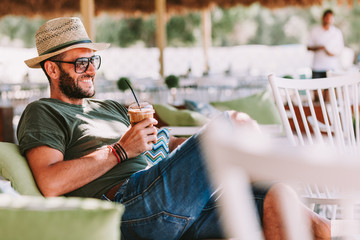Young man drinking ice coffee in a beach bar