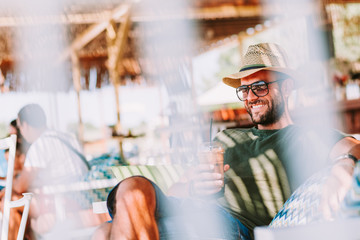 Young man drinking ice coffee in a beach bar