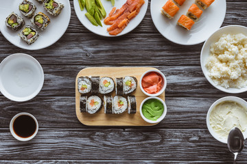 top view of delicious sushi rolls with ingredients on wooden table