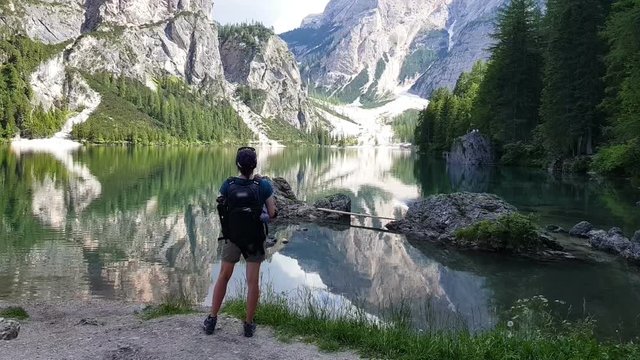 Young girl standing near by beautiful lake in the mountains, Lago Di Braies Italy