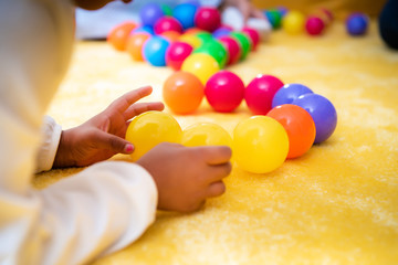 cropped image of african american kid playing with colored balls in kindergarten