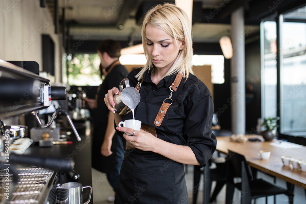 Wall mural Young woman at barista school learning how to make espresso coffee.