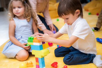 adorable kids playing with constructor in kindergarten