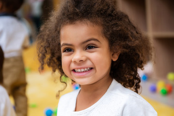 portrait of adorable smiling african american kid looking away in kindergarten