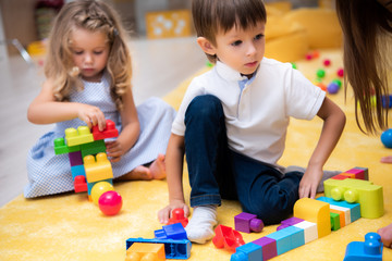 male and female kids playing with constructor in kindergarten