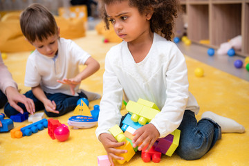 upset african american kid taking constructor pieces in kindergarten