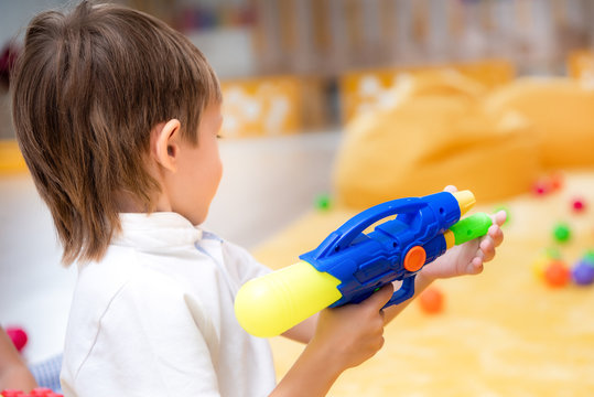side view of boy playing with water gun in kindergarten