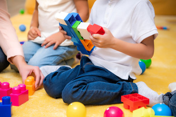 cropped image of tutor and kids playing with constructor in kindergarten