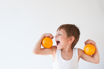 hungry healthy cute little boy wants to eat orange on his biceps muscle