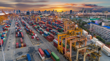 Fototapeta premium Container warehouse from sea port of ship container with beautiful sky and downtown of cityscape background. Can use for import export, international shipping concept.