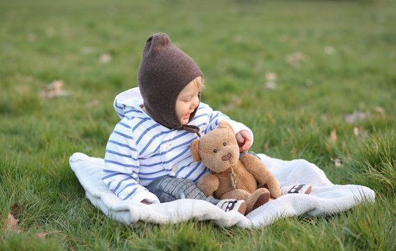 B&eacute;b&eacute; au parc assis parterre avec son doudou en pleine nature
