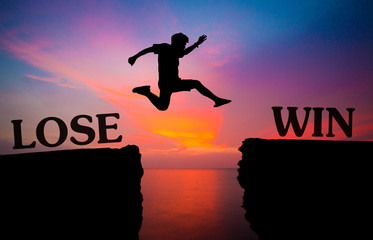 man jump over through the gap between word lose and win on hill.image for background. jump through...