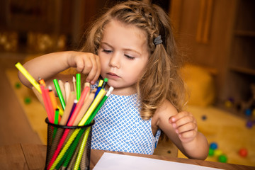 adorable kid choosing colored felt tip pen for drawing in kindergarten