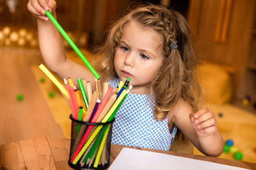adorable child taking green felt tip pen for drawing in kindergarten