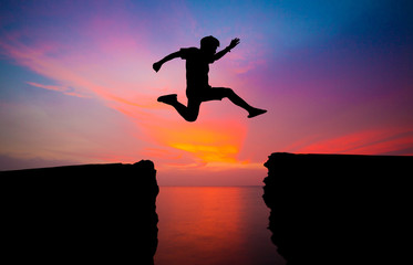 man jump over through on the gap of hill silhouette light, blue sky and sun on background.image for spirit and brave concept.spirit man is representative of success in the past and gold for the future