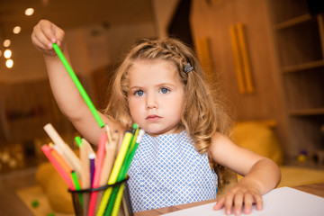 adorable kid taking green felt tip pen for drawing in kindergarten