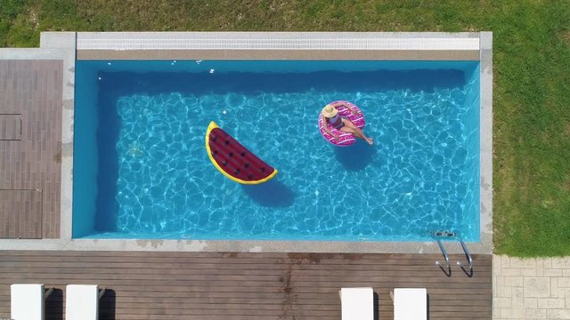 Aerial - Young happy woman relaxing on inflatable donut floatie