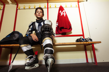 Boy getting ready for hockey game in locker room