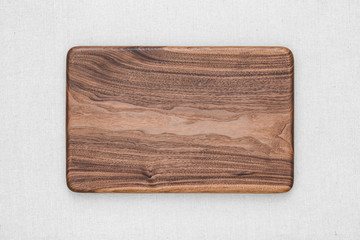 Handmade black walnut rectangular chopping board on burlap, walnut texture background	